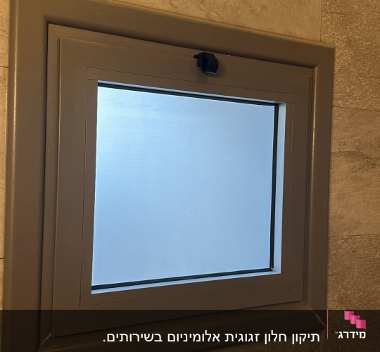 חלון זכוכית עם מסגרת מתכת על קיר אריחים